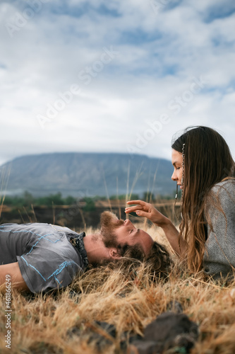 Beautiful, stylish couple lies on the grass and enjoys the moment, against the backdrop of the mountains.