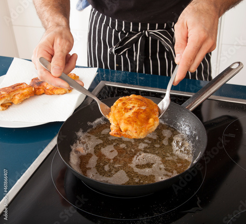 Manos de cocinero friendo pollo. Chef's hands frying chicken