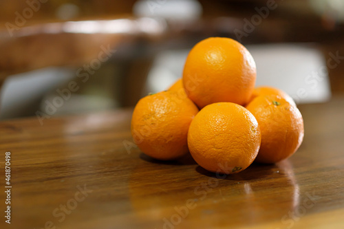 Fresh organic Oranges on the brown wooden table. Navel Oranges stack freshly picked. Front view.