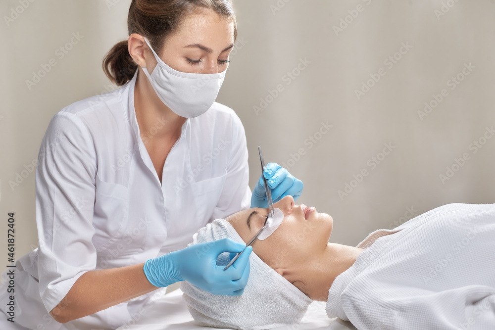 Eyelashes extensions. Fake eyelashes. Eyelash extension procedure. Portrait of woman Professional stylist lengthening female lashes and client in beauty salon. Eyelashes extensions. Fake eyelashes. Eyelash extension procedure. Portrait of woman Professional stylist lengthening female lashes and client in beauty salon.