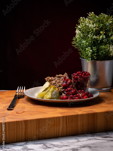 Traditional Finnish cuisines; closeup of sautéed reindeer on a plate with lingonberry jam and pickles on the side.