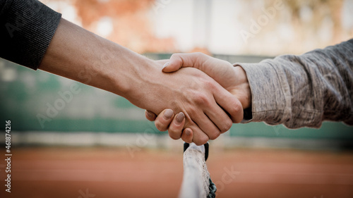 Handshake over the net on the clay tennis court court. Close-up.