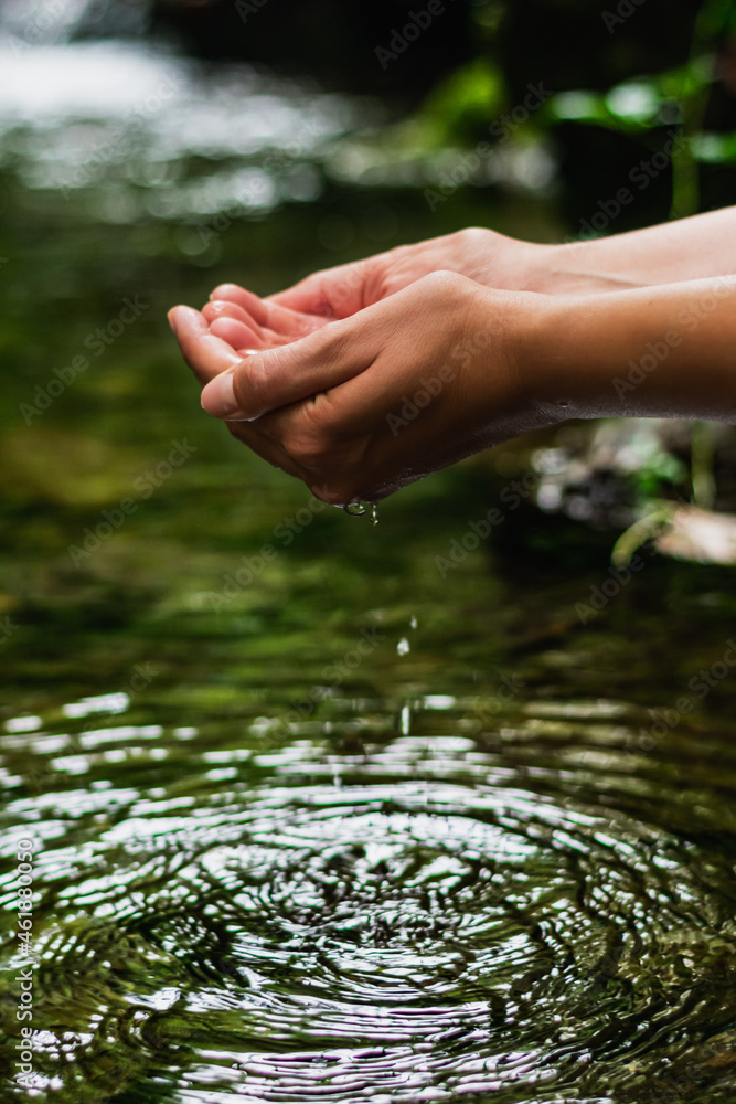 Beautiful male hands taking fresh water from the crystal-clear river