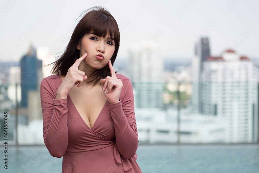 Playful happy woman doing asian pose by pointing at herself