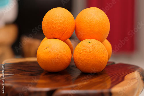 Fresh organic Oranges on the brown wooden table. Two stacks of Navel Oranges freshly picked. Horizontal composition. Front view.