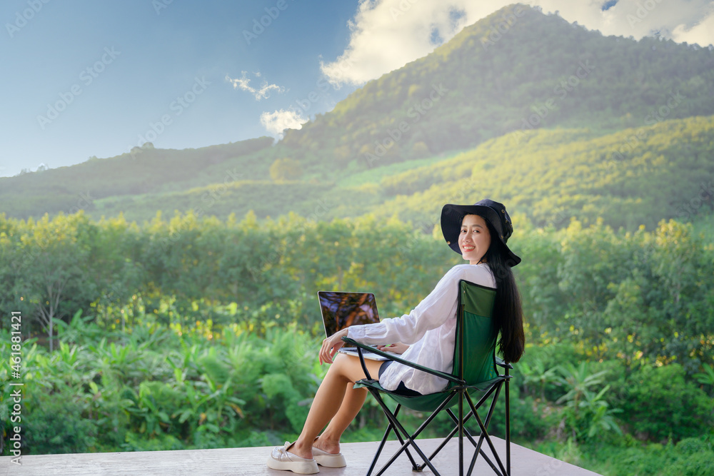 Asian female tourists visiting Thailand Travel that she likes to travel in style. Forests and natural waterfalls beautiful mountains Work on a happy holiday with freelance work on a laptop.