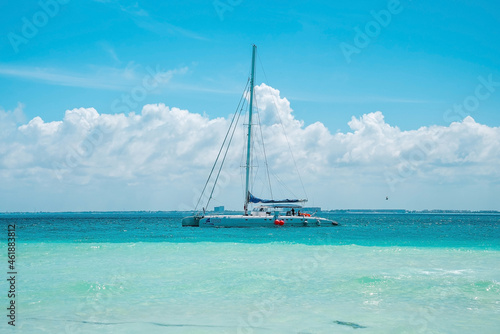 Cancun, Mexico. May 30, 2021. Yacht or sailboat sailing on beautiful turquoise sea water surface against cloudy sky