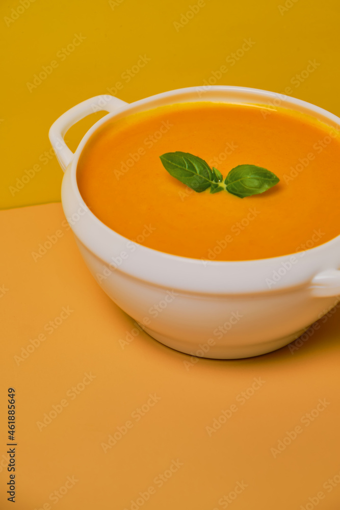 Pumpkin soup decorated basil on orange background Pumpkin soup decorated basil on orange background