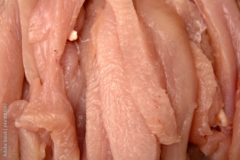 Photo of sliced chicken meat on a dark cutting board with cut marks Photo of sliced chicken meat on a dark cutting board with cut marks