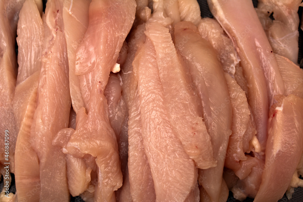 Photo of sliced chicken meat on a dark cutting board with cut marks Photo of sliced chicken meat on a dark cutting board with cut marks