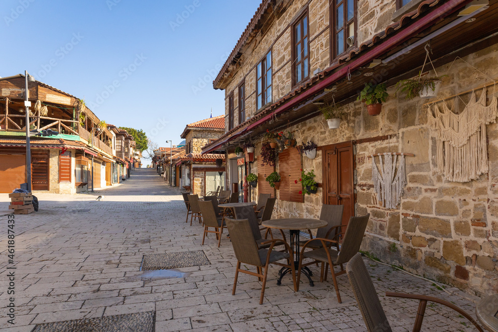 Cobbled street of old city with empty tables in street cafe, flowers in early morning, Side, Turkey