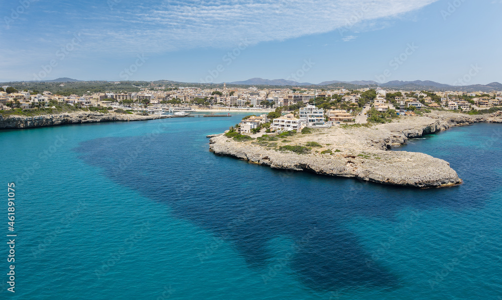 Aerial view of the bay of Porto Cristo as seen from the sea. A nice view of the city and its port. In the background the mountains of the Spanish Mediterranean island of Mallorca are in the sunshine.