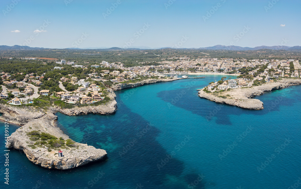 Aerial view of the bay of Porto Cristo on the Spanish Mediterranean island of Mallorca in the sunshine. In the foreground the blue sea and in the background the port and the city.