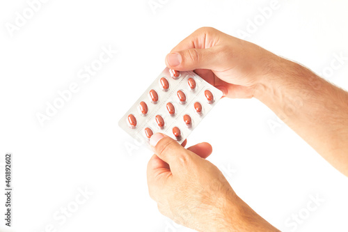 Holding blister pack of brown pills isolated on white background