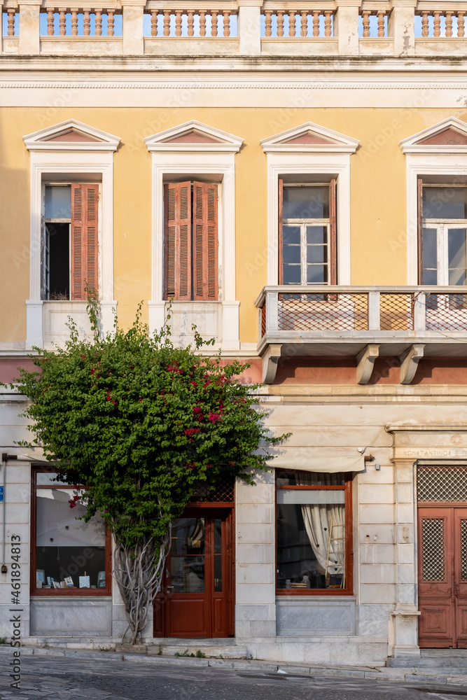 Bougainvillea with red flowers in front of building at Ermoupoli Syros island Greece. Vertical