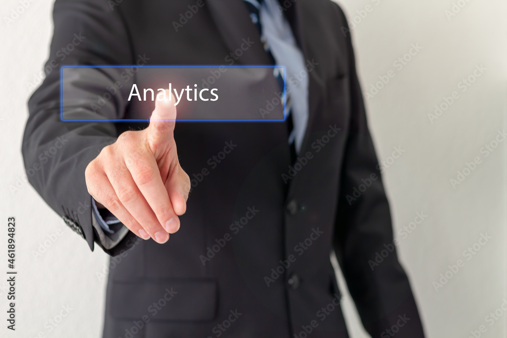 A Businessman is pressing a virtual button with the word Analytics A Businessman is pressing a virtual button with the word Analytics