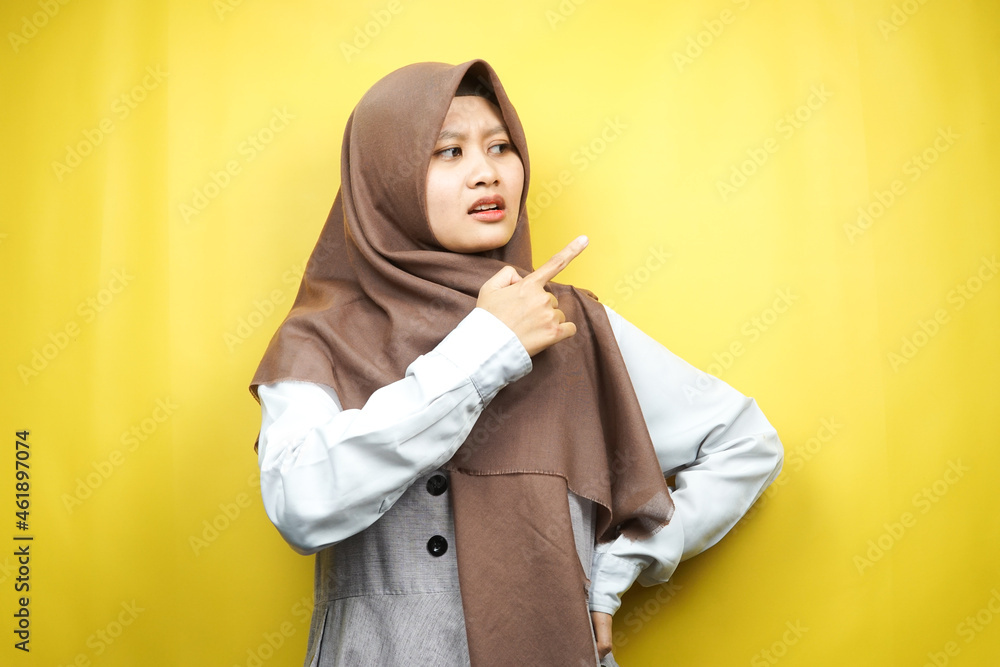 Beautiful young asian muslim woman shocked, surprised, wow expression, with hand pointing to empty space, presenting something, presenting product, isolated on yellow background Beautiful young asian muslim woman shocked, surprised, wow expression, with hand pointing to empty space, presenting something, presenting product, isolated on yellow background