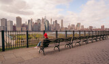 woman cold red cap sitting views skyline New York City skyscrapers buildings sea bridge Manhattan river relax 