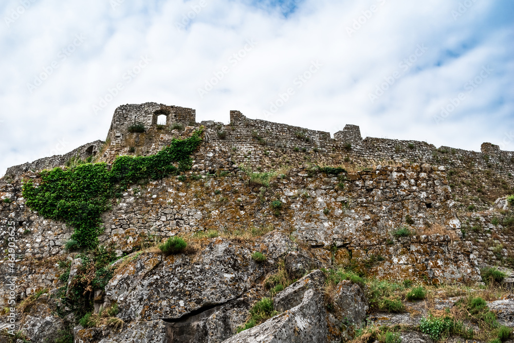 Exterior view of the ancient stone walls of the Rozafa Castle in Shkoder (Albania). The dilapidated facade of a medieval fortress, overgrown with plants