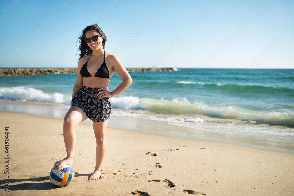 Teenage girl with volleyball ball. Cute girl in sunglasses standing at sea cost. Waves and blue sky in background. Family, vacation, outdoor activity concept Teenage girl with volleyball ball. Cute girl in sunglasses standing at sea cost. Waves and blue sky in background. Family, vacation, outdoor activity concept