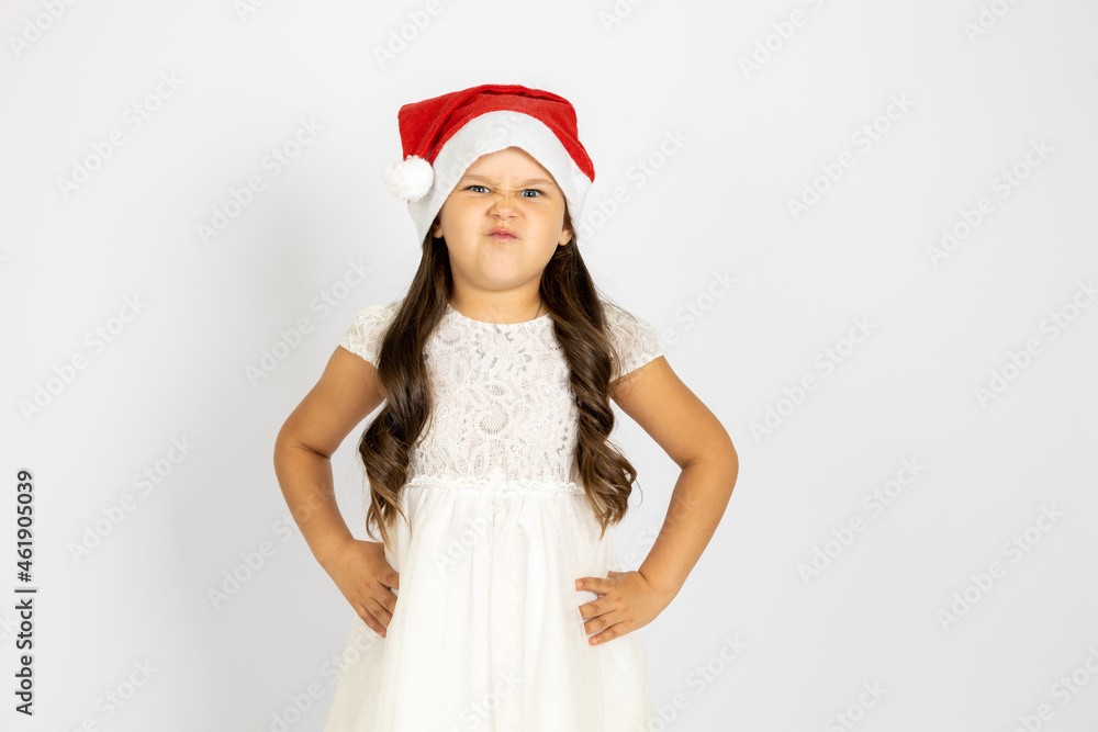 portrait of frowning, dissatisfied girl in Santa Claus hat with hands on waist, isolated on white background, concept of dissatisfaction with New Year gift. portrait of frowning, dissatisfied girl in Santa Claus hat with hands on waist, isolated on white background, concept of dissatisfaction with New Year gift.
