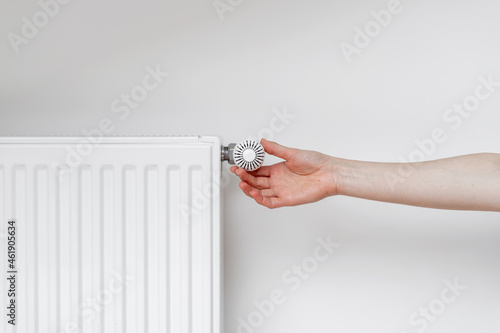 Woman adjusting thermostat on white heating radiator photo