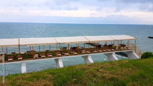 4K VIDEO, Empty aerarium with sun loungers on the background of grass and the sea in the morning, luxury vacation photo