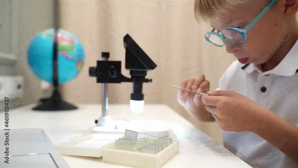 Schoolboy in uniform studies a specimen under the microscope Schoolboy in uniform studies a specimen under the microscope