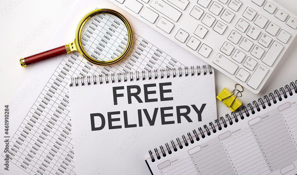 Fototapeta premium FREE DELIVERY text written on a notebook on chart with keyboard and planning