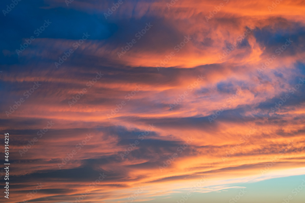 Clouds are lit up orange and pink by the light of the low sun. Suitable as background or wallpaper.