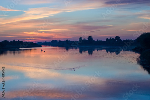 Łódka wędkarze na rzece w pięknym oświetleniu zachodzącego słońca odbicia kolorowych chmur w wodzie 