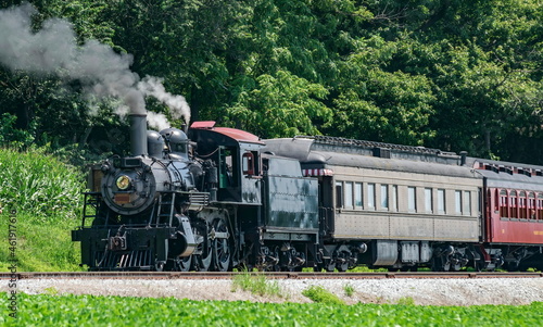 View of an Antique Restored Steam Passenger Train Blowing Smoke and Steam on a Sunny Summer Day