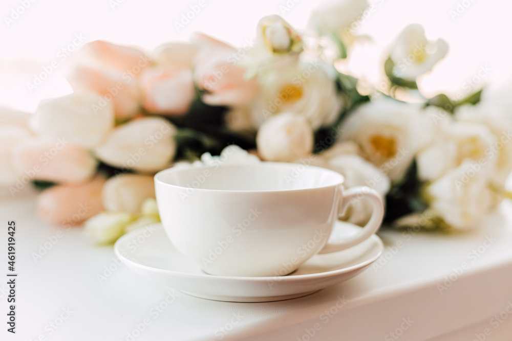 A cup of morning coffee on a background of white tulips A cup of morning coffee on a background of white tulips