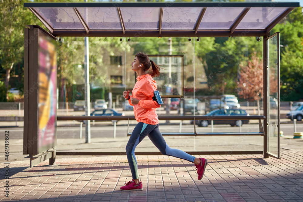 Fit millennial girl in sportswear run with cellphone