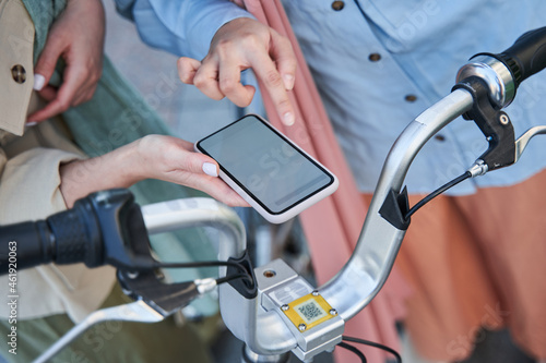 Two women hands using smartphone to unlocking bike for walking through the city