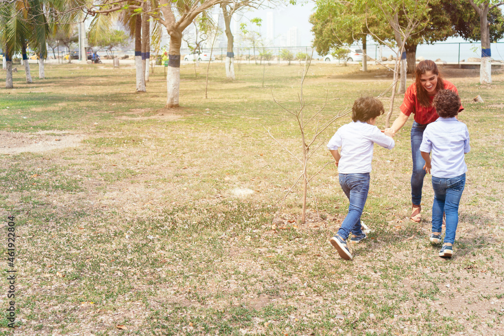 A young mother and her young children playing in the park.