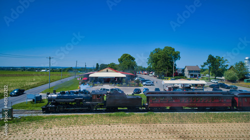 Aerial View of a Steam Train Puffing Smoke and Steam Passing People at a Motel Going Thru the Farmlands