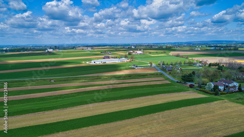 A Beautiful Aerial View of Farm Countryside with Patches of Colored Fields with White Fully Clouds and Shadows