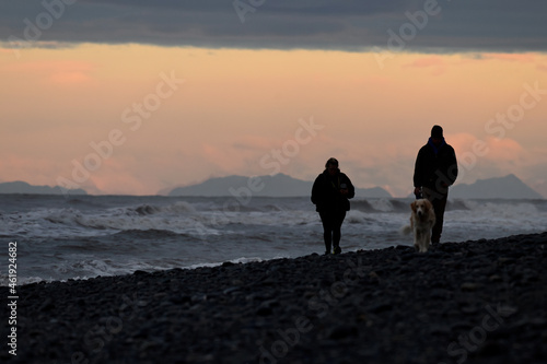 Silhouette of people walking on the beach at sunset in Homer, Alaska.