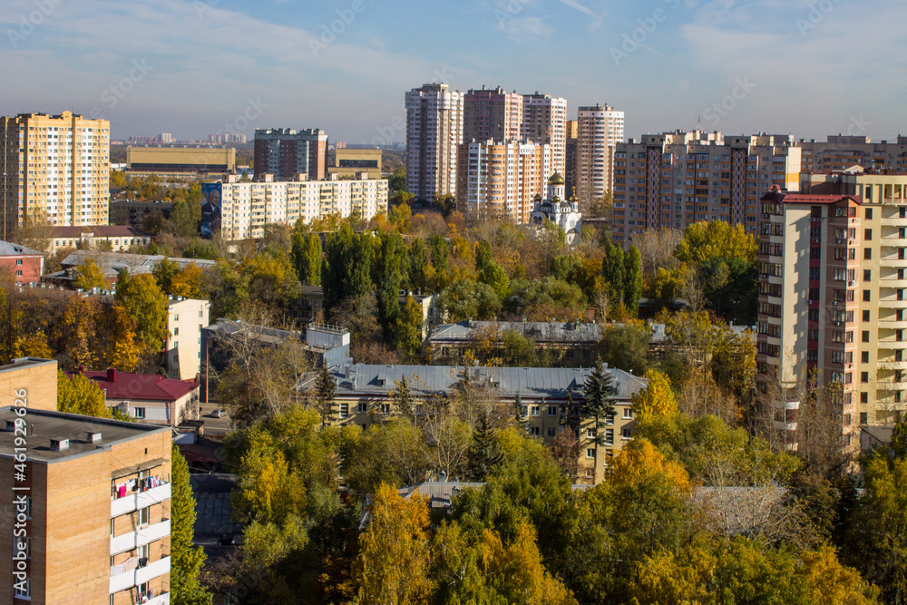 Panoramic top view of modern city houses among autumn trees with colorful foliage and blue sky on a clear October day. Concept urban landscape in Reutov, Moscow region and copy space