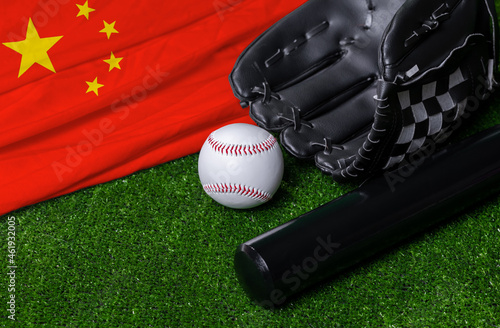 Baseball bat, glove and ball near China flag on green grass background