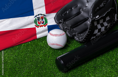 Baseball bat, glove and ball near Dominican republic flag on green grass background