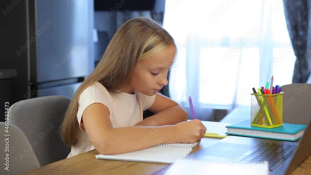 Schoolgirl studies online using a modern laptop. Homework Schoolgirl studies online using a modern laptop. Homework