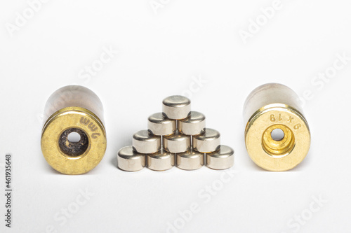 Reloading/handloading - closeup of 9mm brass/casing showing dirty(Left) and cleaned(Right) primer pocket with stack of pistol primers.