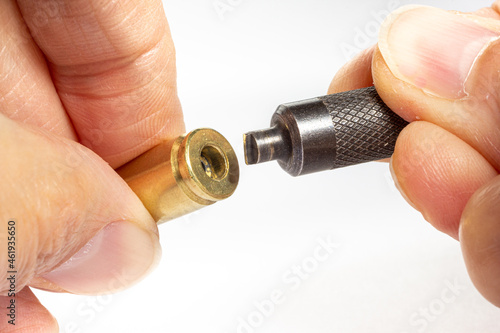 Reloading/handloading - closeup of 9mm Brass/casing primer pocket being cleaned and prepared for new pistol primers.