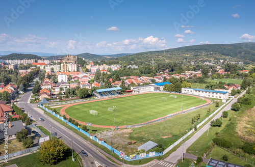old versus new in Fialkovo Slovakia, modern residence building, soccer field with medieval hilltop castle ruin in the background © tamas