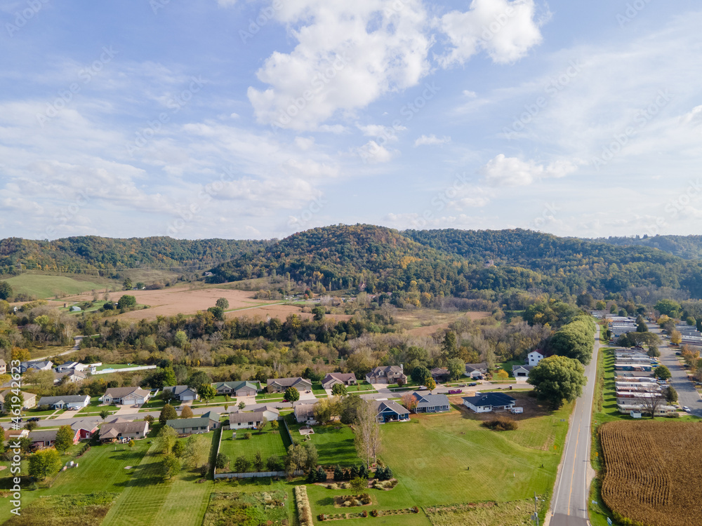 rural neighborhood and farm land in autumn in midwest; mountains with trees and open landscape; farm fields after harvest; family friendly single-family homes and mobile home park for diversity.   