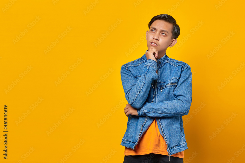 portrait of unhappy looking young asian man holding chin with raised hand and looking up portrait of unhappy looking young asian man holding chin with raised hand and looking up