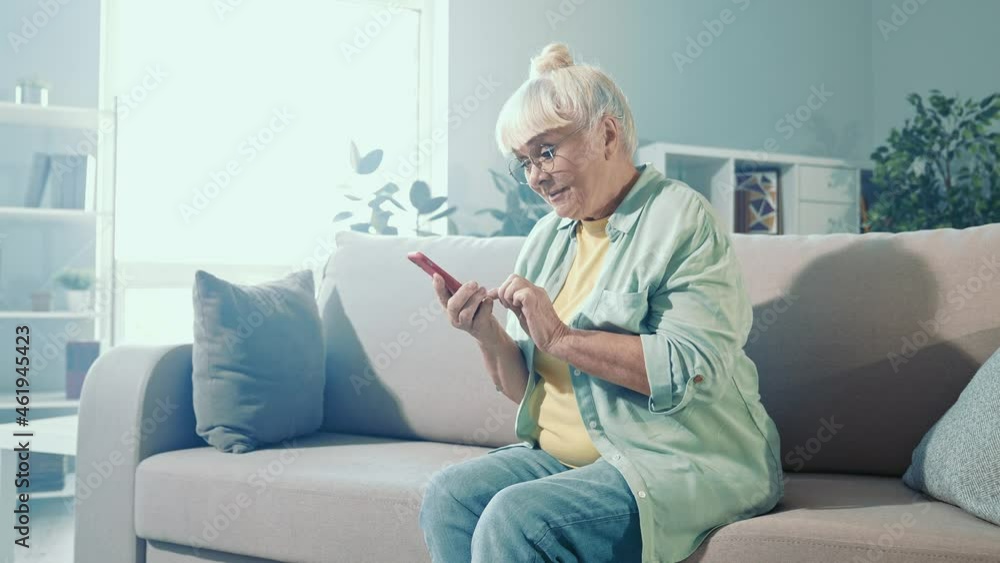 Curious grandma sit comfy couch hold telephone scroll internet feed Curious grandma sit comfy couch hold telephone scroll internet feed