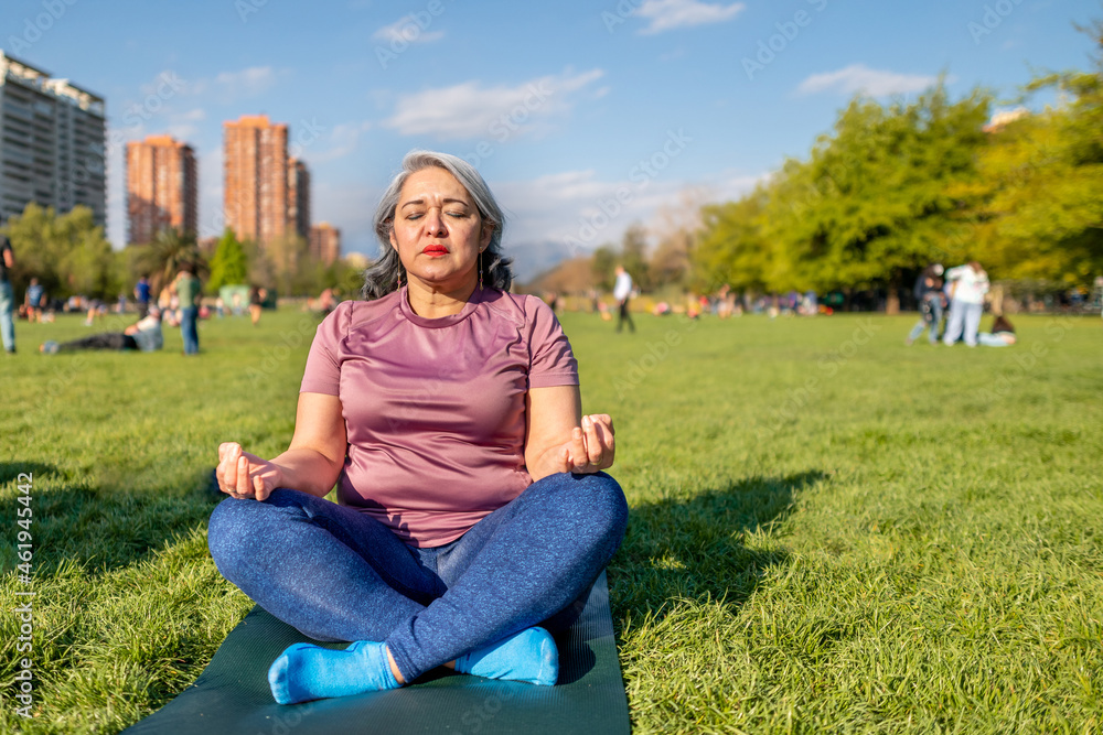 Mature woman doing yoga the lotus pose outdoor at an urban park Mature woman doing yoga the lotus pose outdoor at an urban park